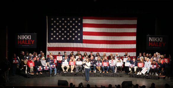 Nikki Haley supports in front of a large American flag on stage at one of her rallies.